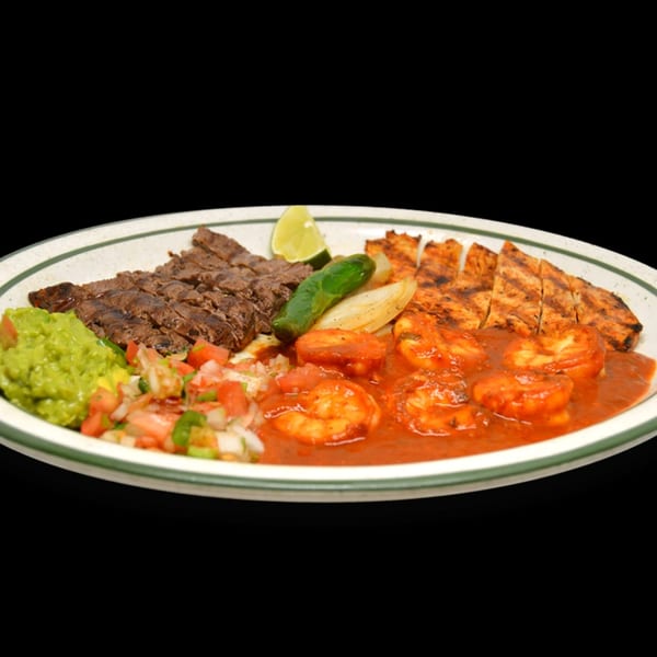 A Mexican platter with grilled steak, chicken, shrimp in red sauce, guacamole, pico de gallo, and lime.